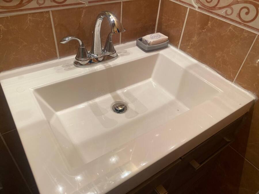 Ein weißes Waschbecken mit chromfarbenem Wasserhahn und einer Seifenschale.