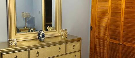 A bedroom with a bed, dresser, TV, and wooden closet.