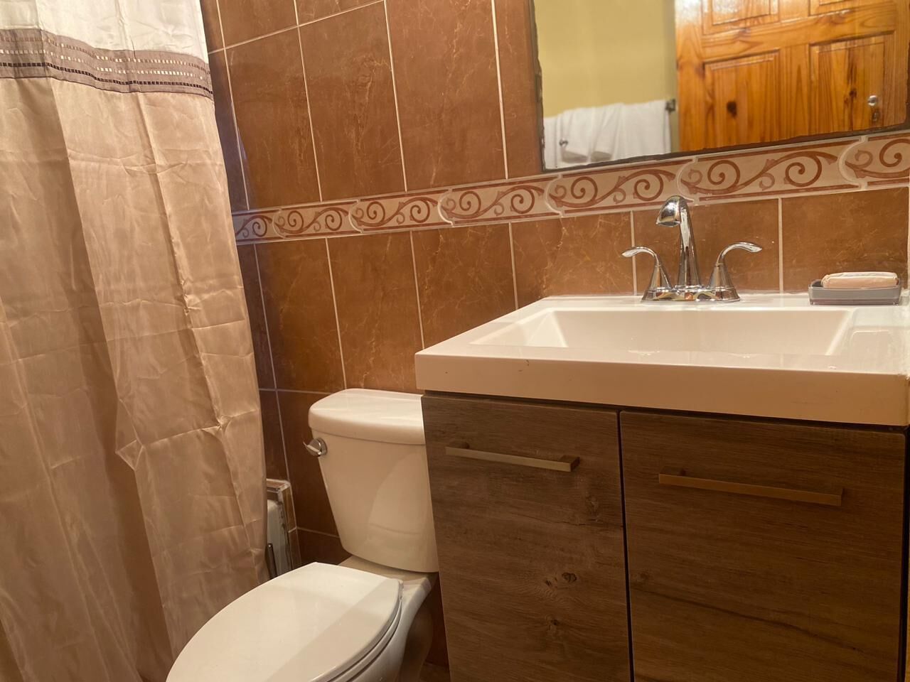 A bathroom with a toilet, sink, and mirror.