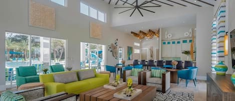 Un vestíbulo amplio con un sofá amarillo brillante, sillones verde azulado y una mesa de centro de madera.