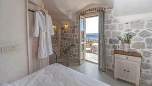 Een slaapkamer met een stenen muur, een bed, een nachtkastje, een spiegel en uitzicht.