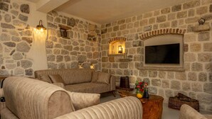 Een gezellige woonkamer met stenen muren, een grote flatscreen televisie en comfortabele zithoek.