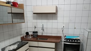 A compact kitchen with a sink, countertop, and a stove. - Ótimo Apartamento Vista Mar Pé na Areia (Praia Grande)