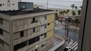 A multi-story building with a parking area and a view of the beach. - Ótimo Apartamento Vista Mar Pé na Areia (Praia Grande)