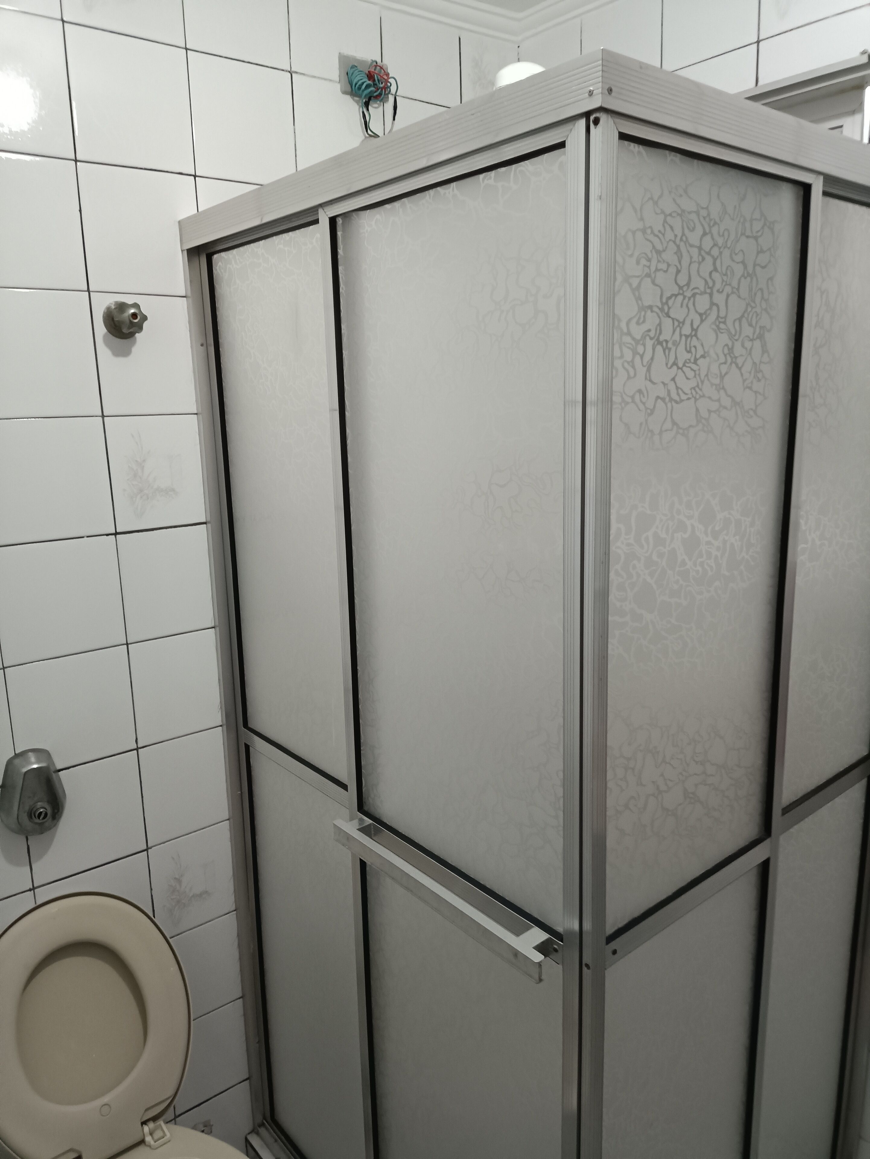 A bathroom with a toilet, a shower enclosure, and tiled walls.