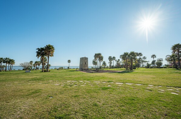 A grassy park with a stone monument, palm trees, and a clear sky. - Beautiful house, a 5-minute walk from the beach (ESTEPONA)