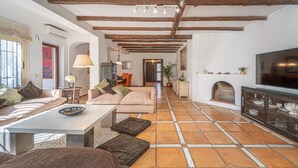 Ein geräumiges Wohnzimmer mit Kamin, Fernseher und einem Essbereich mit Tisch und Stühlen.