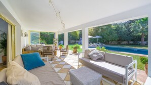 Eine überdachte Terrasse mit Pool, Gartenmöbeln und Blick auf den Hinterhof.