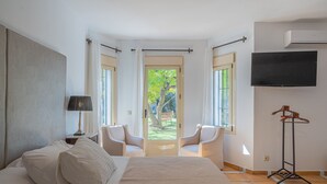 Ein Schlafzimmer mit einem Bett, zwei Stühlen, einem Fernseher und einem Kleiderhaken.