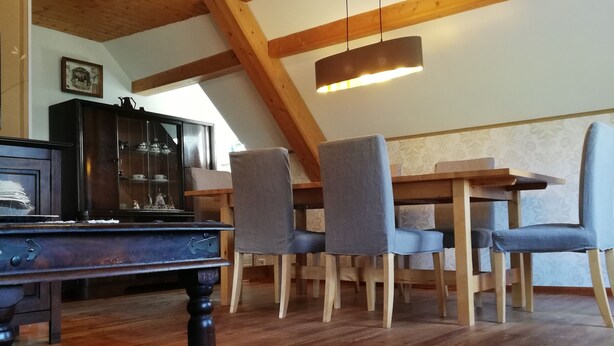 Una habitación estilo loft acogedora, con techo de madera, una mesa de comedor con sillas, un aparador de madera oscura y una pequeña alfombra.