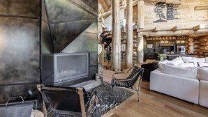 A modern log cabin interior with a fireplace, seating area, and kitchen. - 7 bed 6 bath cottage on Lake Muskoka (Gravenhurst)