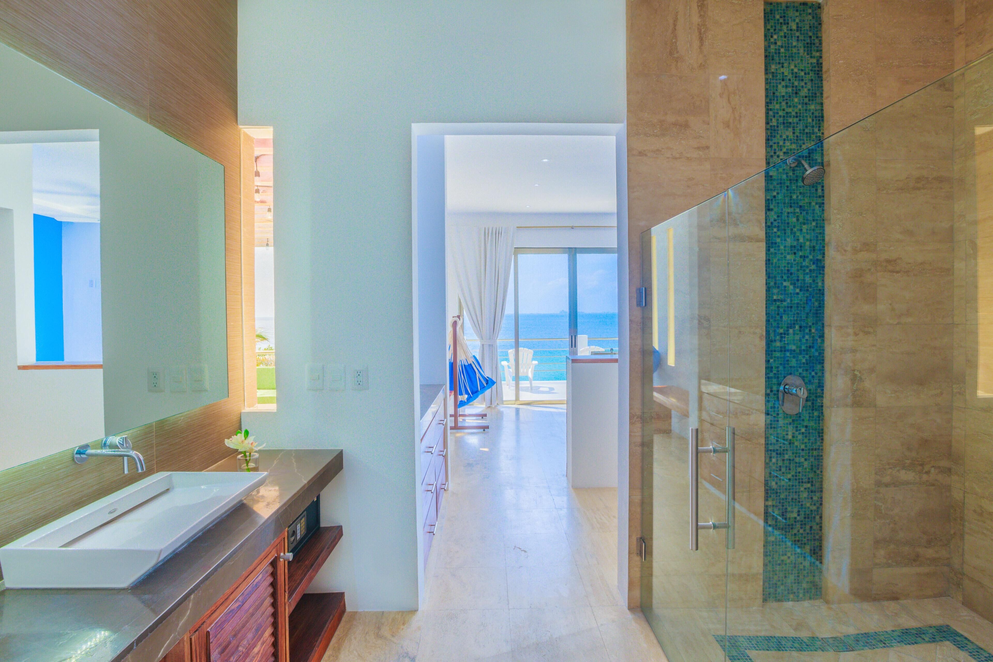 A modern bathroom with a large mirror, a sink, and a shower.