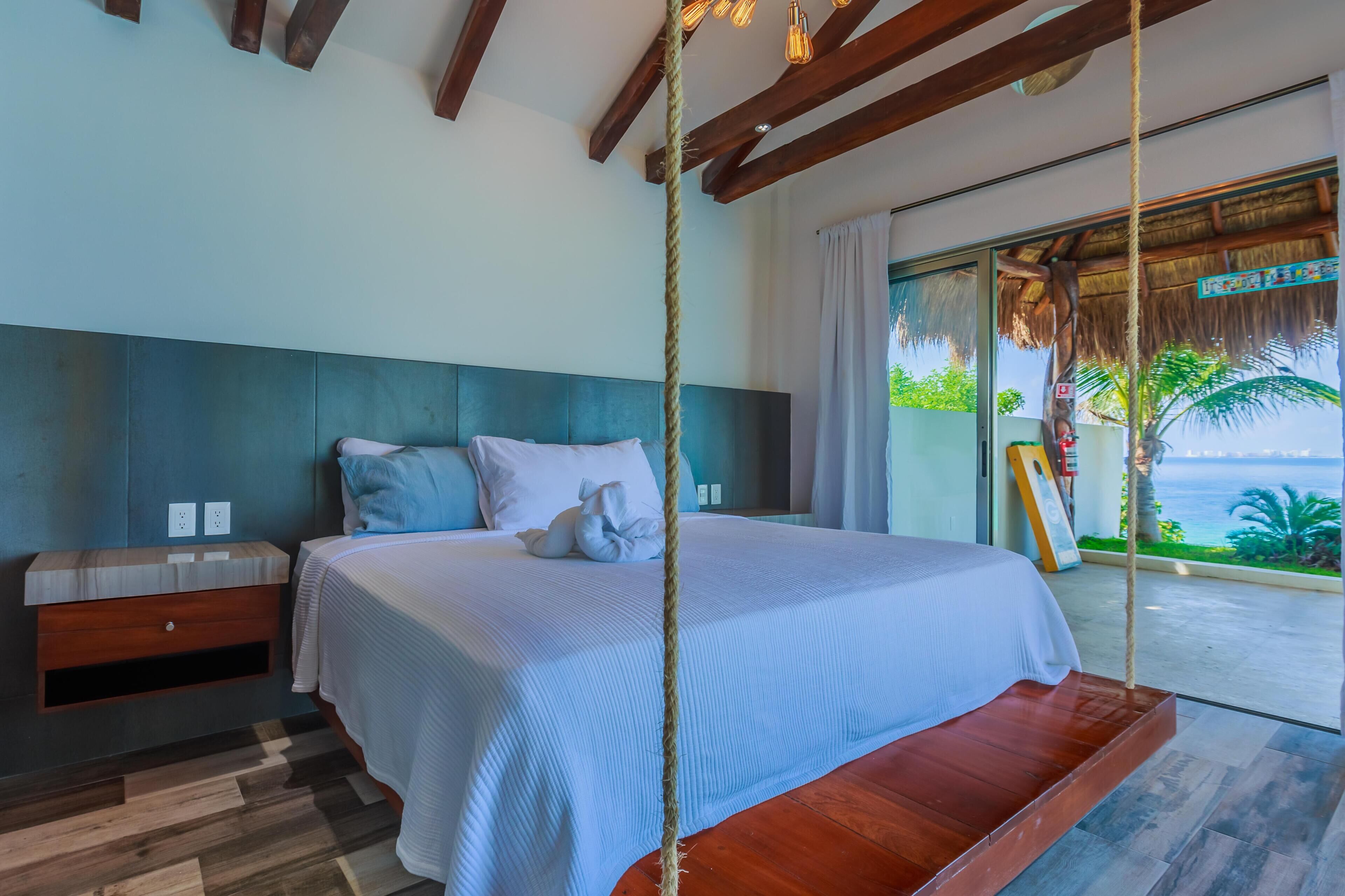 A bedroom with a bed, bedside table, and a view of the ocean.
