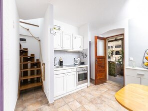 Une cuisine de taille réduite, avec des meubles blancs, une table en bois et une vue sur l’extérieur.