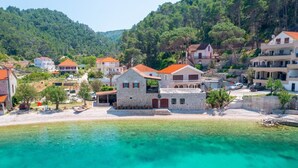 Un borgo costiero con edifici in pietra, un mare cristallino color turchese e una formazione rocciosa a forma di cuore.