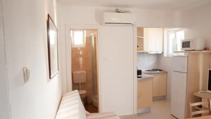 Eine kompakte, moderne Wohnung mit Küchenzeile, einem kleinen Badezimmer und einem Wohnbereich mit Sofa.