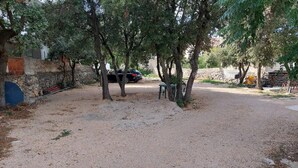 Ein Parkplatz mit Kiesbefestigung, Bäumen und einer Steinmauer.