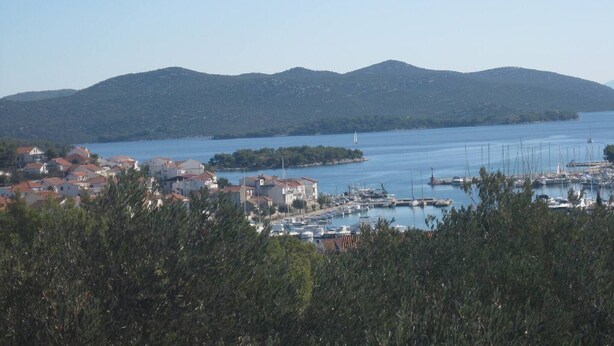 Eine Küstenstadt mit einem Yachthafen, Häusern und Hügeln im Hintergrund.