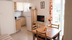 Eine kleine Küche mit Kühlschrank, Herd, Mikrowelle und einem Essbereich mit Tisch und Stühlen.