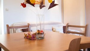 A dining area with a wooden table, chairs, and a vase with flowers. - Apartments Paula - One Bedroom Apartment with Terrace 2 (Jezera)