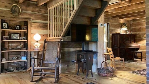 Ein rustikales Holzinnere mit Treppe, Kamin und Holzboden.