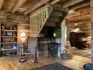 A rustic wooden interior with a staircase, a fireplace, and a wooden floor.