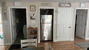 A kitchen with a stainless steel refrigerator, wooden cabinets, and a dining table with chairs. - Cozy Country Cottage #2 (Miller Place)