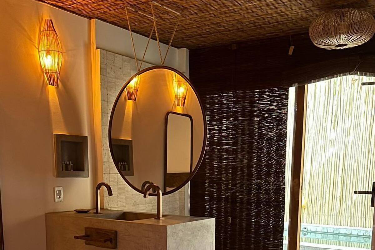 Een hotelkamer met een groot bed, een ronde spiegel, een wastafel en uitzicht op buiten.