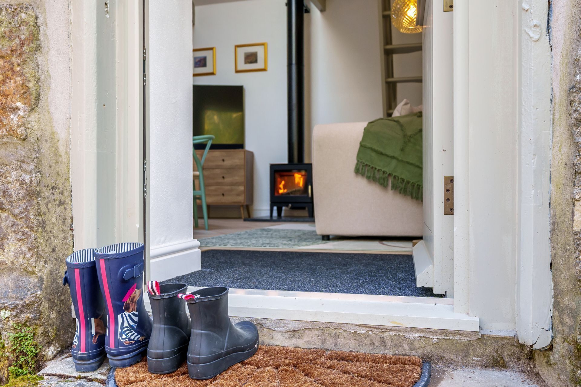 A doorway leading to a living room with a fireplace, a sofa, and a green blanket.