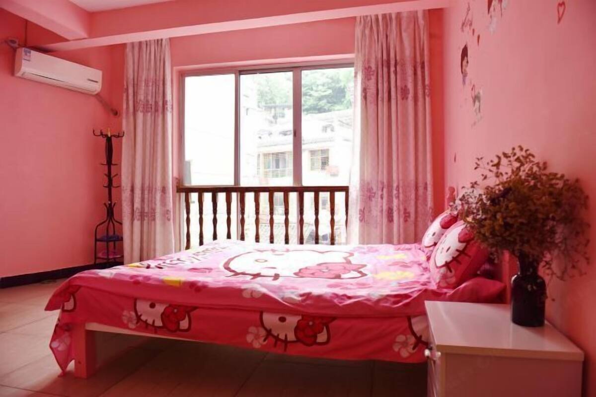 A pink-themed bedroom with a bed, a nightstand, a window with curtains, and a wall-mounted air conditioner.