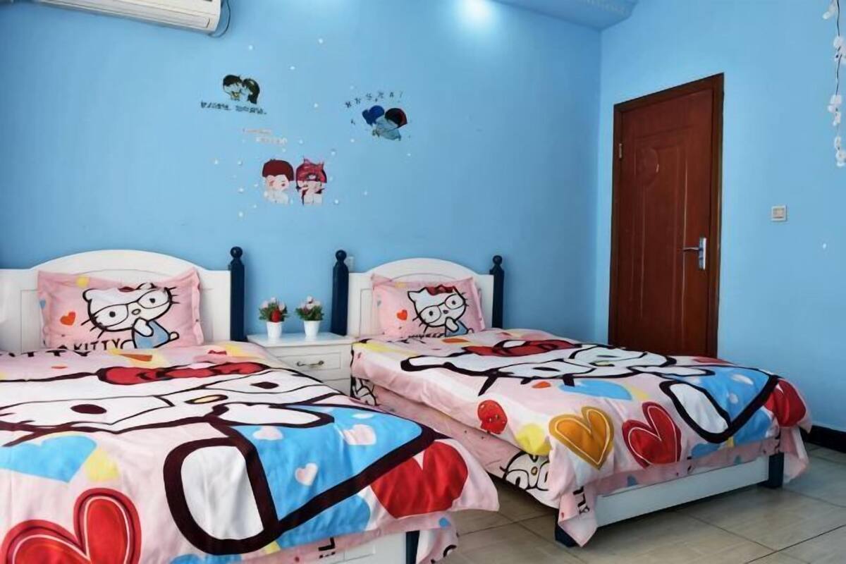 A bedroom with two beds, a wooden door, and wall decorations.
