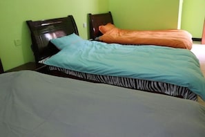 A room with two beds, each with a distinct headboard and pillow.