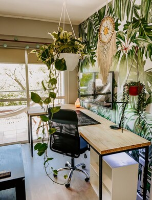 A modern office space with a wooden desk, black office chair, and a large window. - Bright Studio with balcony, hammock and big desk (Paraná)