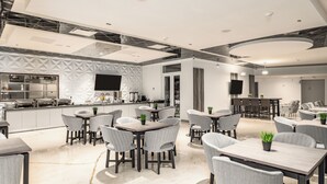 Un espace de repas moderne doté d’un îlot central, de plusieurs configurations de sièges et d’un coin cuisine avec un téléviseur à écran plat.