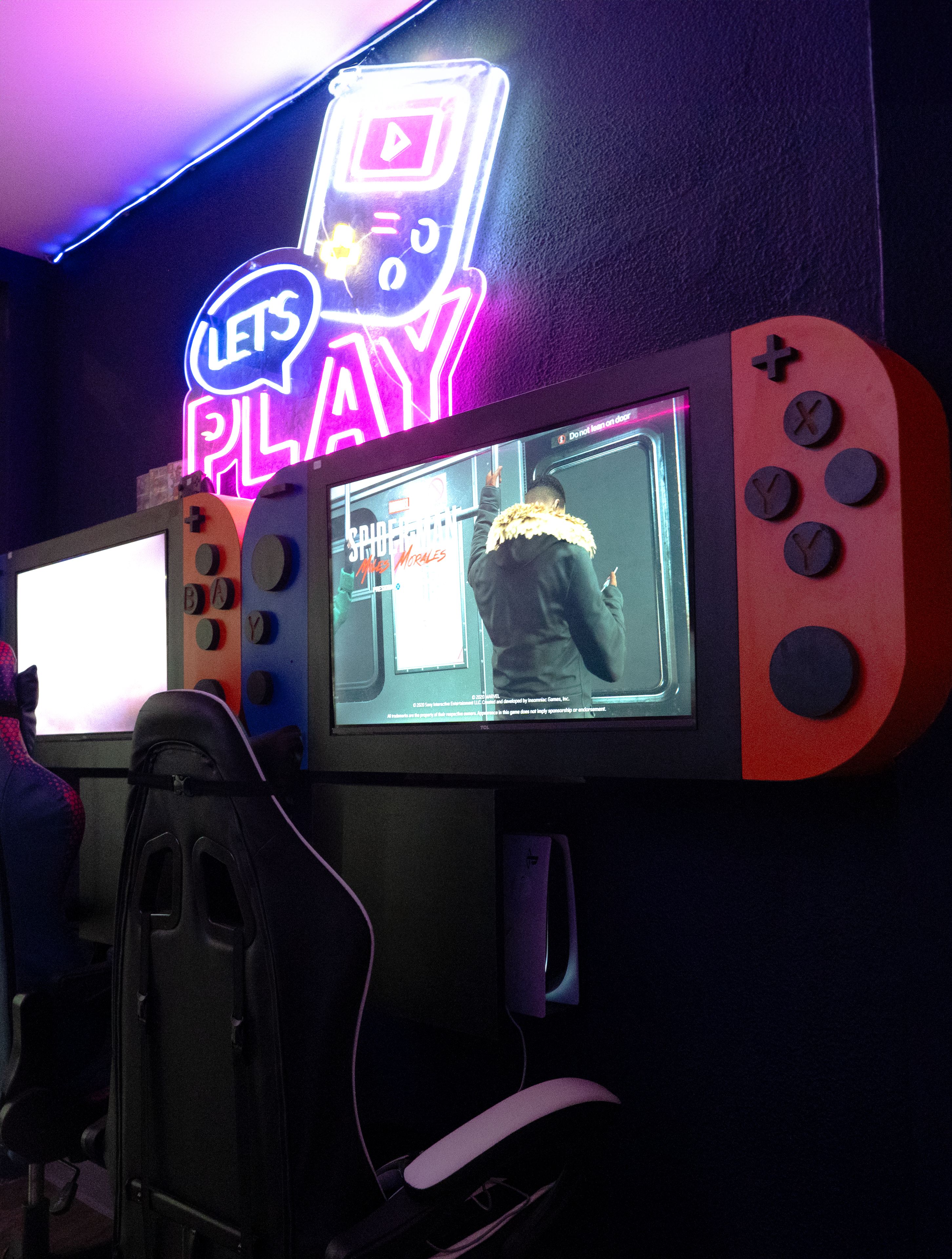 Un equipo de juego con un letrero de neón, una pantalla mostrando un juego y una silla gamer.