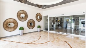 Un hall d’entrée moderne avec un sol en marbre, des miroirs fixés aux murs et des plantes en pot.