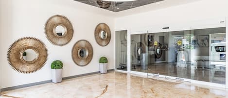 Un vestíbulo moderno con piso de mármol, espejos en la pared y plantas en macetas.