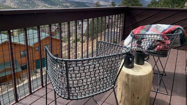 A balcony with a metal chair and a wooden post, overlooking a mountainous landscape with buildings in the background. - Dreamcatcher - 2 bed 2 bath condo with tremdous views! (Estes Park)