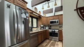 A modern kitchen with stainless steel appliances, wooden cabinets, and a herringbone-patterned floor. - Dreamcatcher - 2 bed 2 bath condo with tremdous views! (Estes Park)
