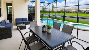An outdoor patio with a pool, seating, and a view of a residential area.