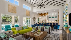 A spacious living area with a pool view, modern furniture, and a kitchen in the background.