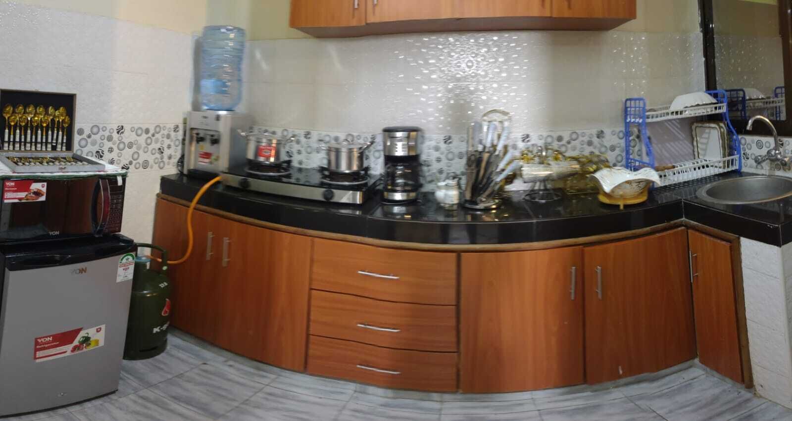 Een koelkast, een magnetron, een kookplaat, kookgerei, borden en bestek