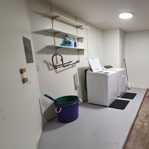 A laundry room with a washing machine, a mop, and a bucket.