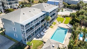 Et hotel med flere etager, en pool, altaner og udsigt til stranden.