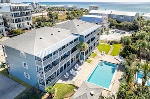 A multi-story hotel with a pool, balconies, and a view of the beach.