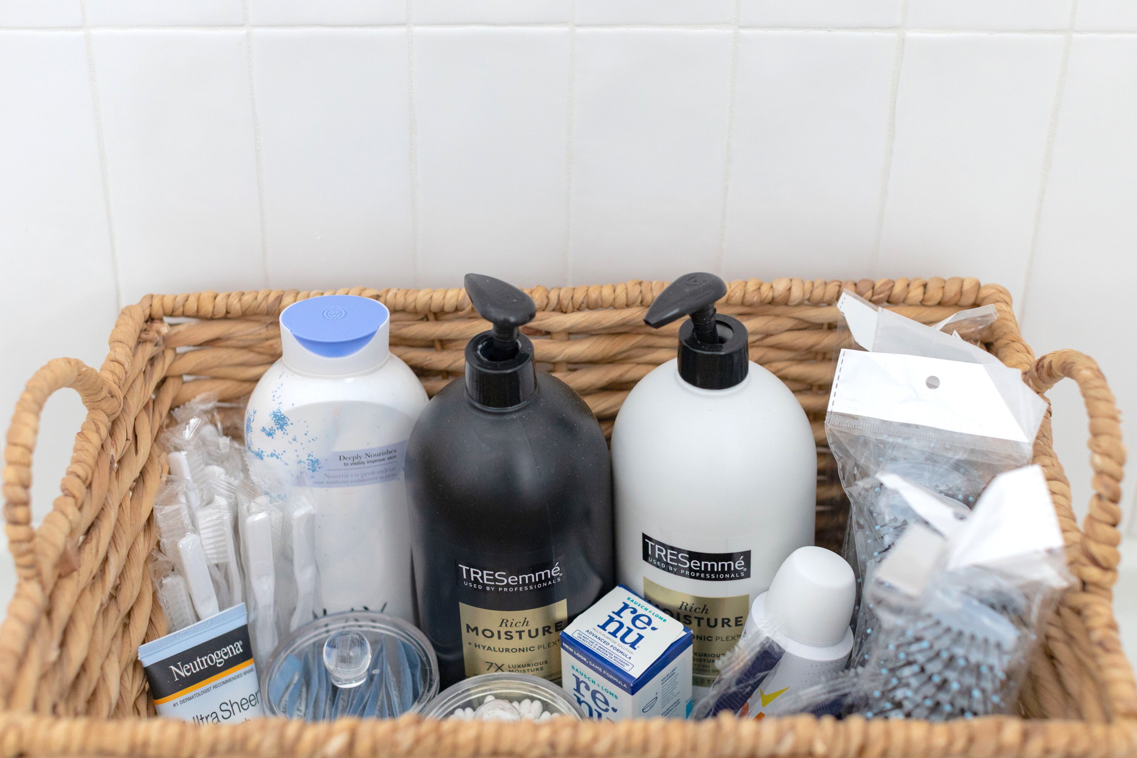 A wicker basket containing toiletries including bottles of TRESemmé, Neutrogena, and other personal care products.
