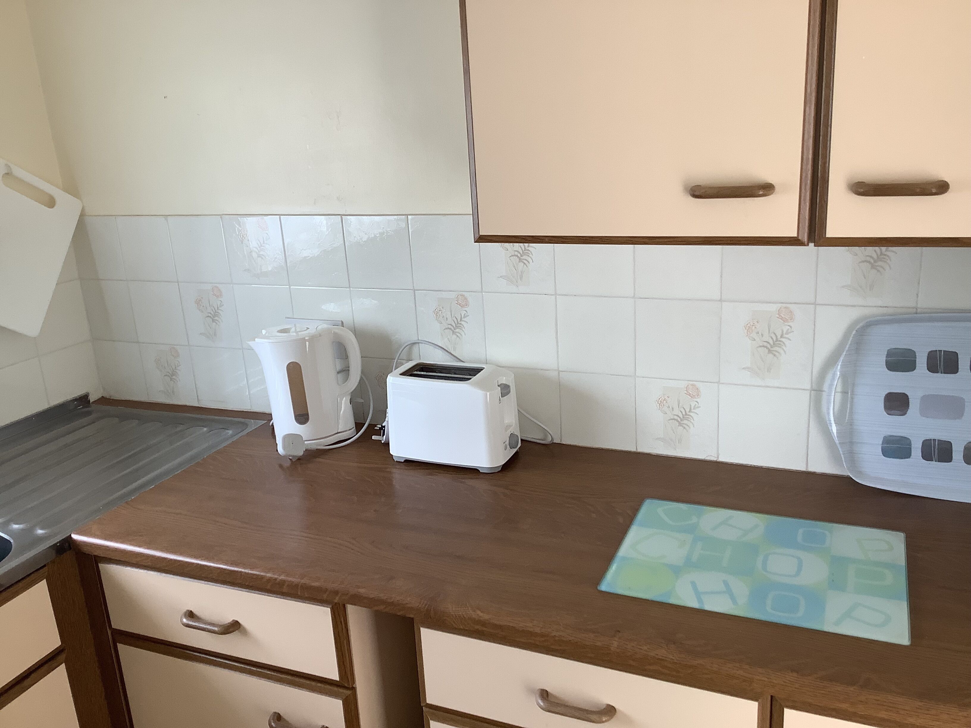 Une cuisine dotée d’un plan de travail en bois, d’une bouilloire, d’un grille-pain et d’un crédence décorée.