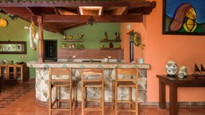 A kitchen with a stone island, wooden chairs, and a tiled floor. - Casa Leona Colonial Home in Downtown Tamarindo (Tamarindo)