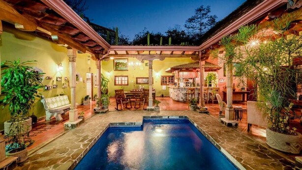 A pool area with a stone floor, surrounded by potted plants and furniture. - Casa Leona Colonial Home in Downtown Tamarindo (Tamarindo)