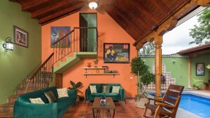 A spacious living area with a green sofa set, a coffee table, and a poolside seating area. - Casa Leona Colonial Home in Downtown Tamarindo (Tamarindo)
